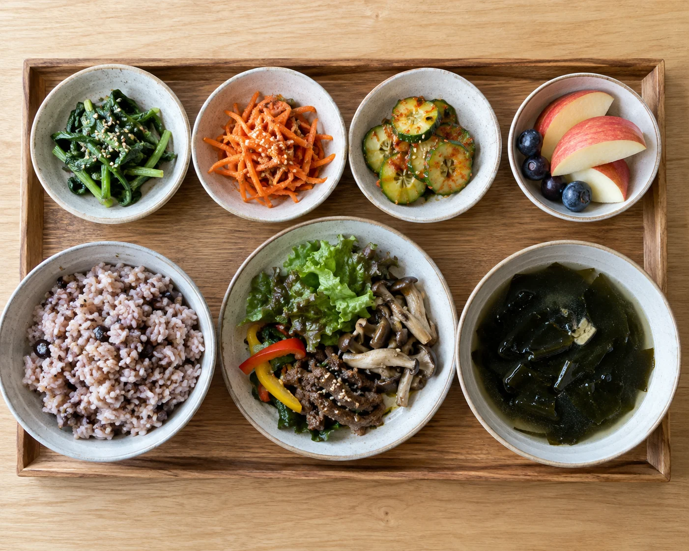 잡곡밥, 나물, 버섯 볶음, 미역국, 과일을 담은 한식 점심 쟁반